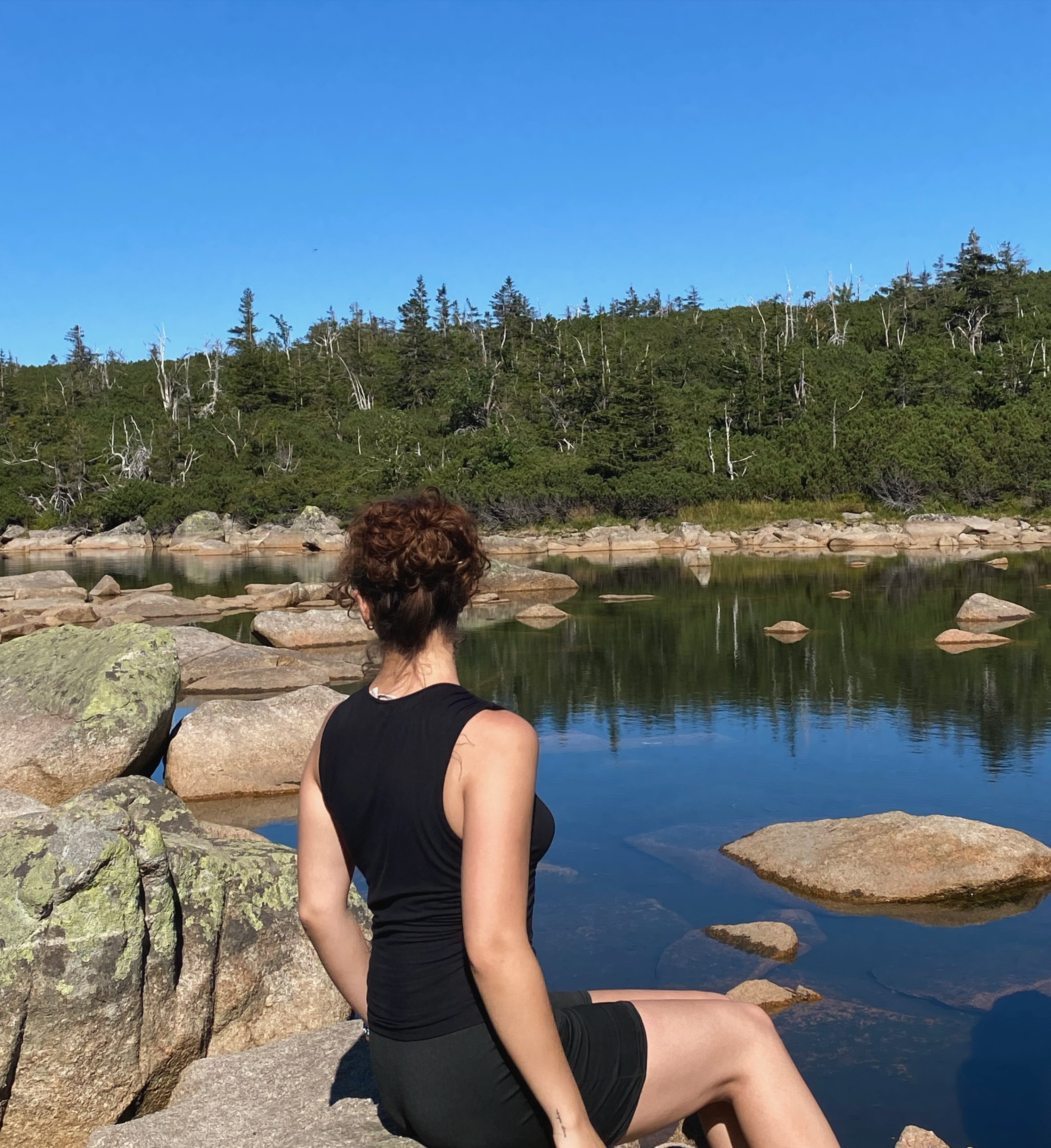 Maja sitting beside a mountain lake